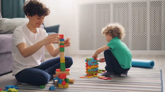 An adult and a child building towers with colorful blocks