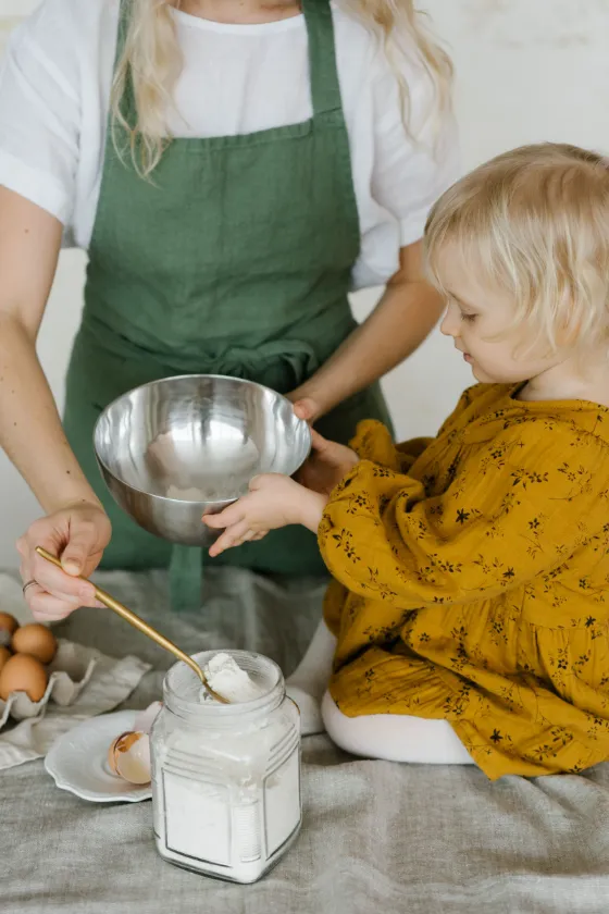 A young child helping an adult mix ingredients in the kitchen