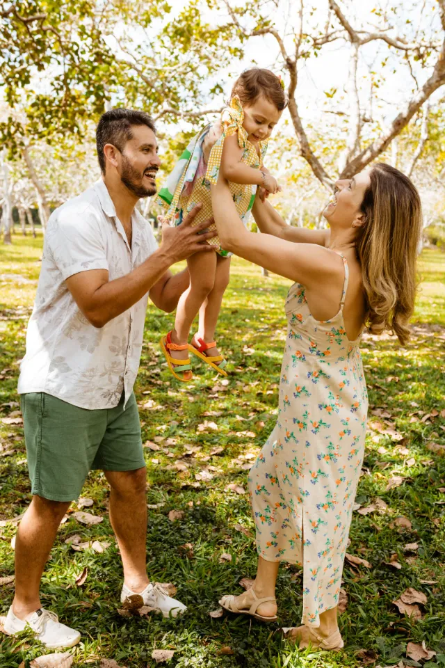Parents playing with their young child in a sunny park