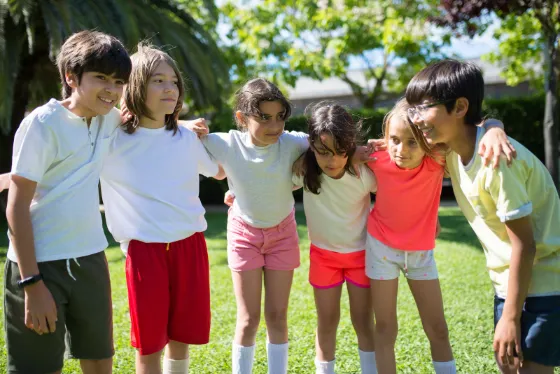 A group of children standing arm in arm in a sunny park